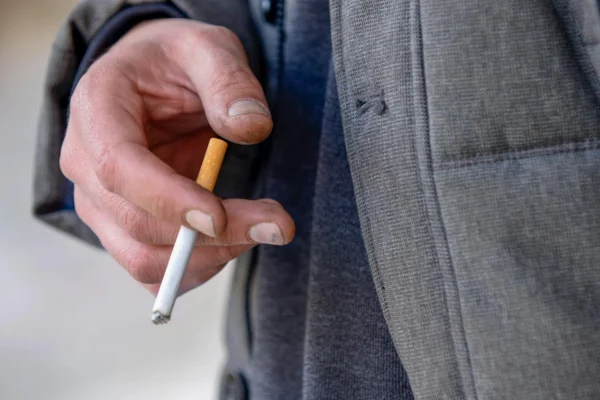 Homem fumando um cigarro após comprar com um comerciante que sabe onde comprar cigarros para revenda